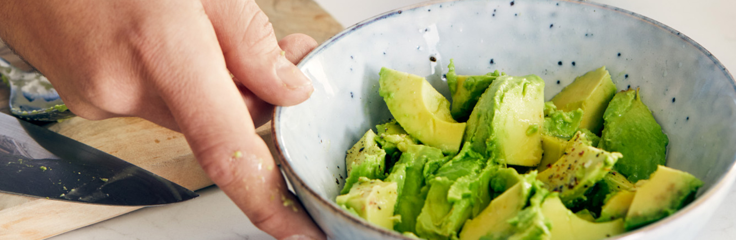 Hand holding a bowl of avocadoes