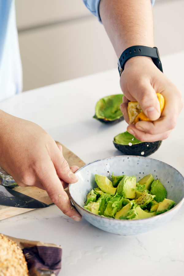 Hand holding a bowl of avocadoes