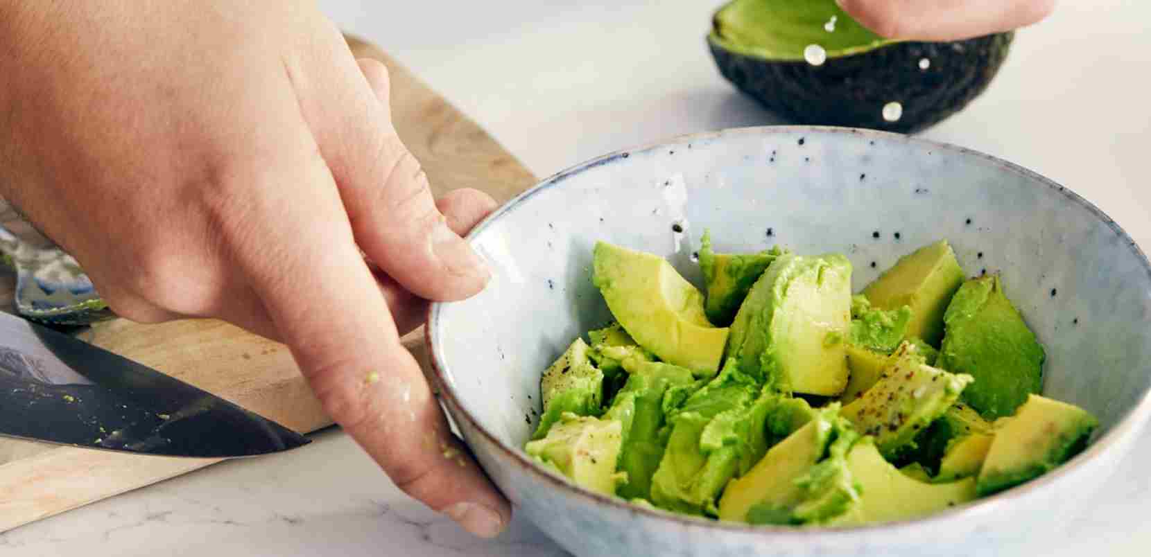 Hand holding a bowl of avocadoes