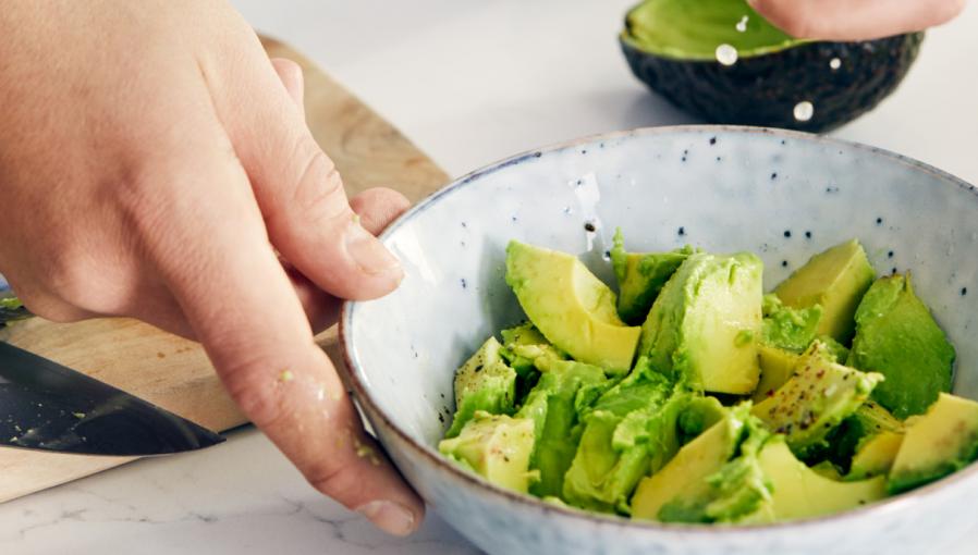 Preparing avocado salad in a bowl as a part of diet meal program